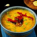 Ein aromatisches indisches Linsengericht (Masoor Dal) aus roten Linsen, serviert in einer Schale, garniert mit frischem Koriander – traditionell zubereitet mit Gewürzen und ideal zu Reis oder Fladenbrot.
