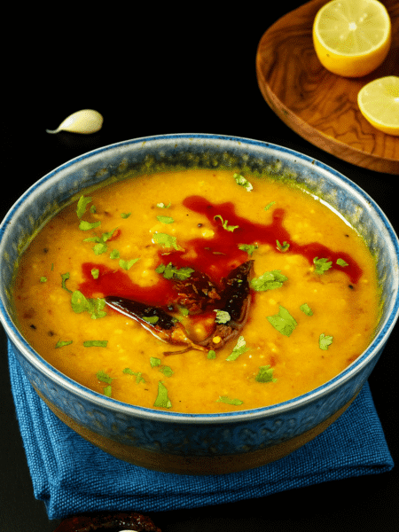 Ein aromatisches indisches Linsengericht (Masoor Dal) aus roten Linsen, serviert in einer Schale, garniert mit frischem Koriander – traditionell zubereitet mit Gewürzen und ideal zu Reis oder Fladenbrot.