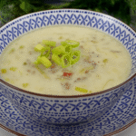 Eine Schale cremige Käse-Lauch-Suppe mit Hackfleisch, serviert in einer blau-weiß gemusterten Keramikschale auf passendem Teller, garniert mit frischen Lauchringen.