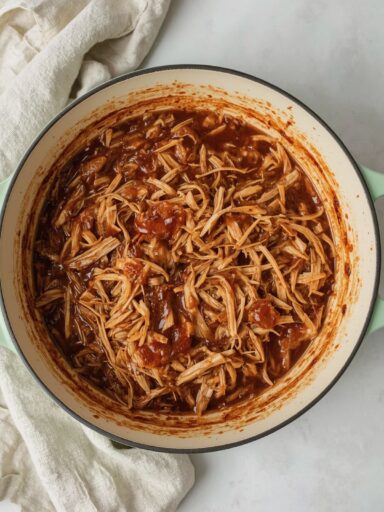 Dutch Oven Pulled Chicken – zart geschmortes Hähnchenfleisch in BBQ-Sauce, serviert direkt im gusseisernen Dutch Oven