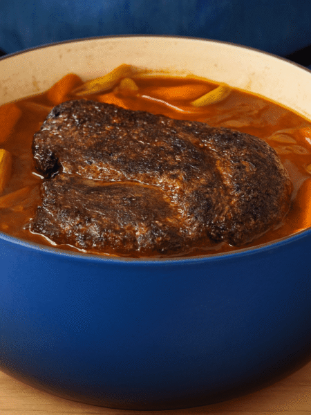 Schmorbraten im blauen Dutch Oven mit Karotten und Sellerie in aromatischer Sauce – frisch aus dem Ofen serviert.