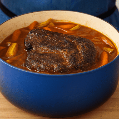 Schmorbraten im blauen Dutch Oven mit Karotten und Sellerie in aromatischer Sauce – frisch aus dem Ofen serviert.