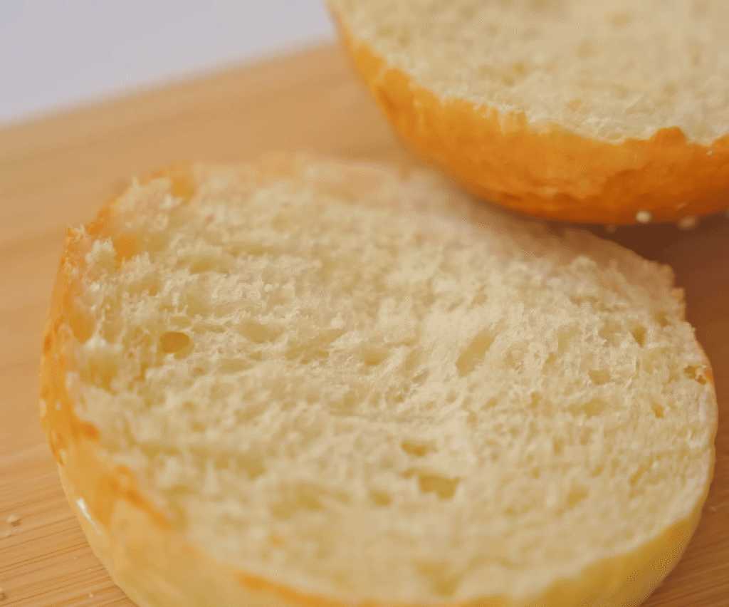 Frisch gebackene, goldbraune Brioche-Brötchen auf einem Holzbrett.