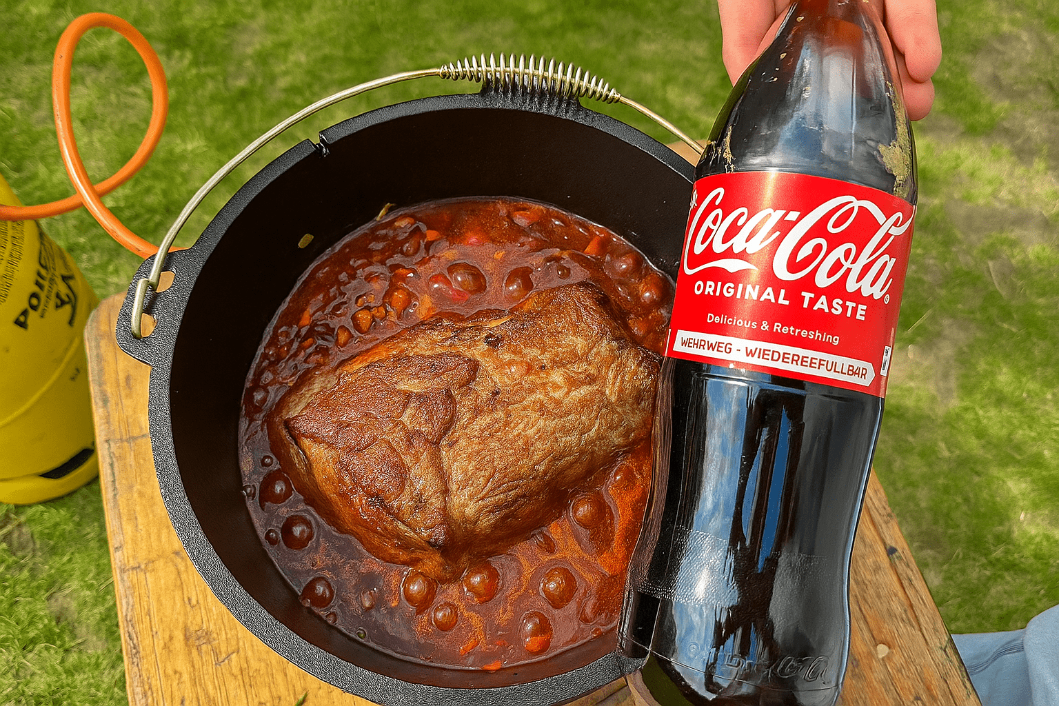 Geschmortes Colafleisch mit Cola, Sauerkirschen und BBQ-Sauce, serviert in einer gusseisernen Pfanne.